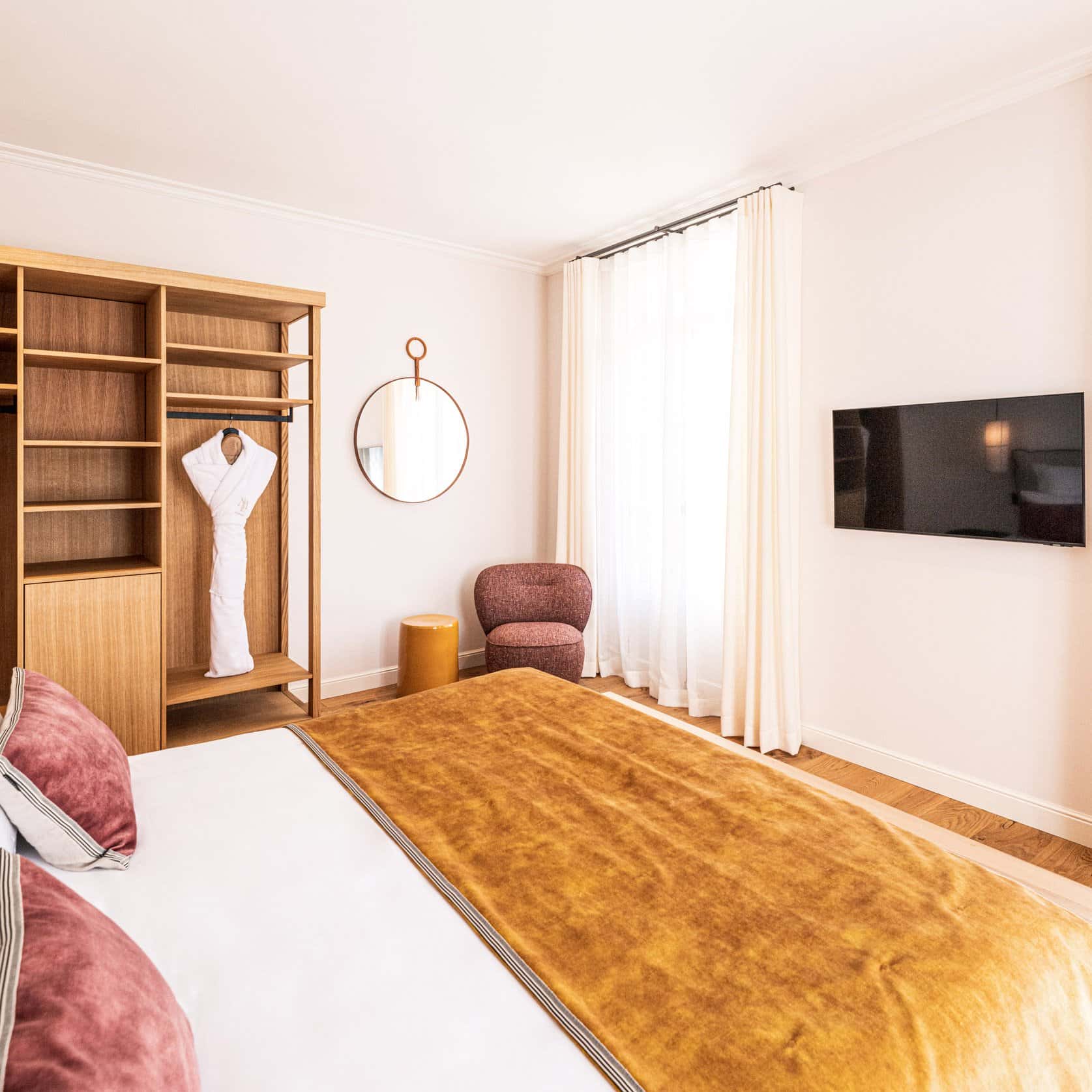 Suite avec TV, armoire et chaise, lit jaune à l'Hôtel Le Mosaïque, Narbonne.