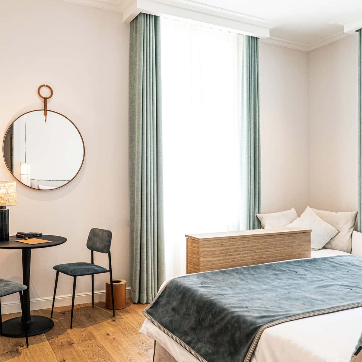Chambre double deluxe à l'Hôtel Le Mosaïque avec lit bleu, miroir et table, ambiance cosy.