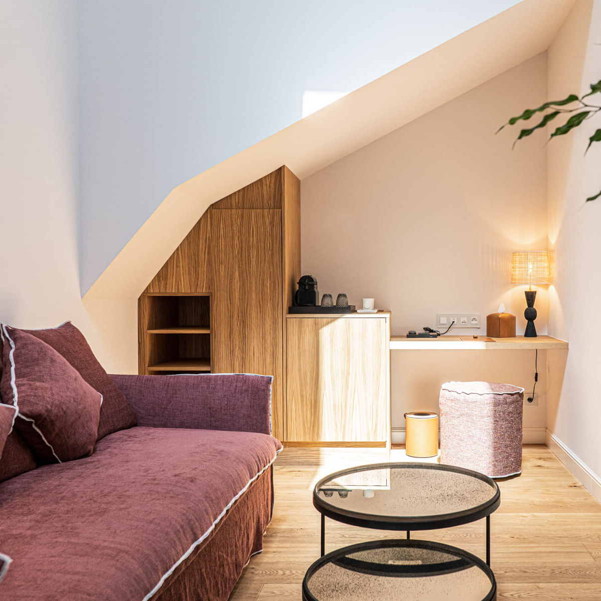 Suite élégante de l'Hôtel Le Mosaïque avec fauteuil et table, ambiance accueillante et chaleureuse.