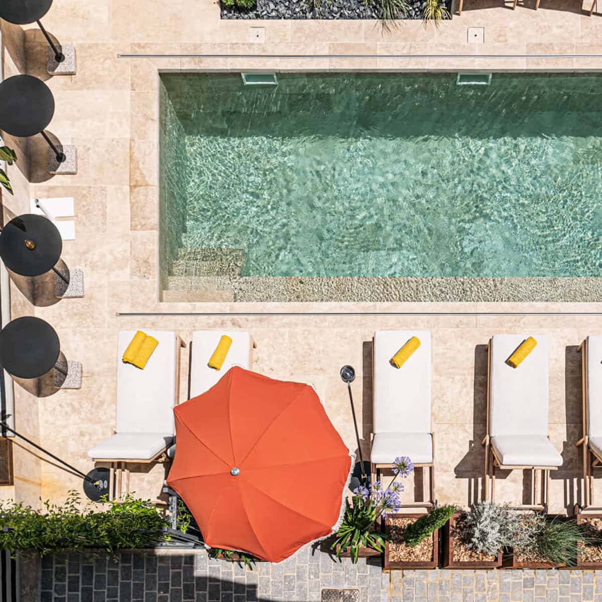 Vue aérienne de la piscine de l'Hôtel Mosaique à Narbonne, montrant l'eau et l'espace détente.